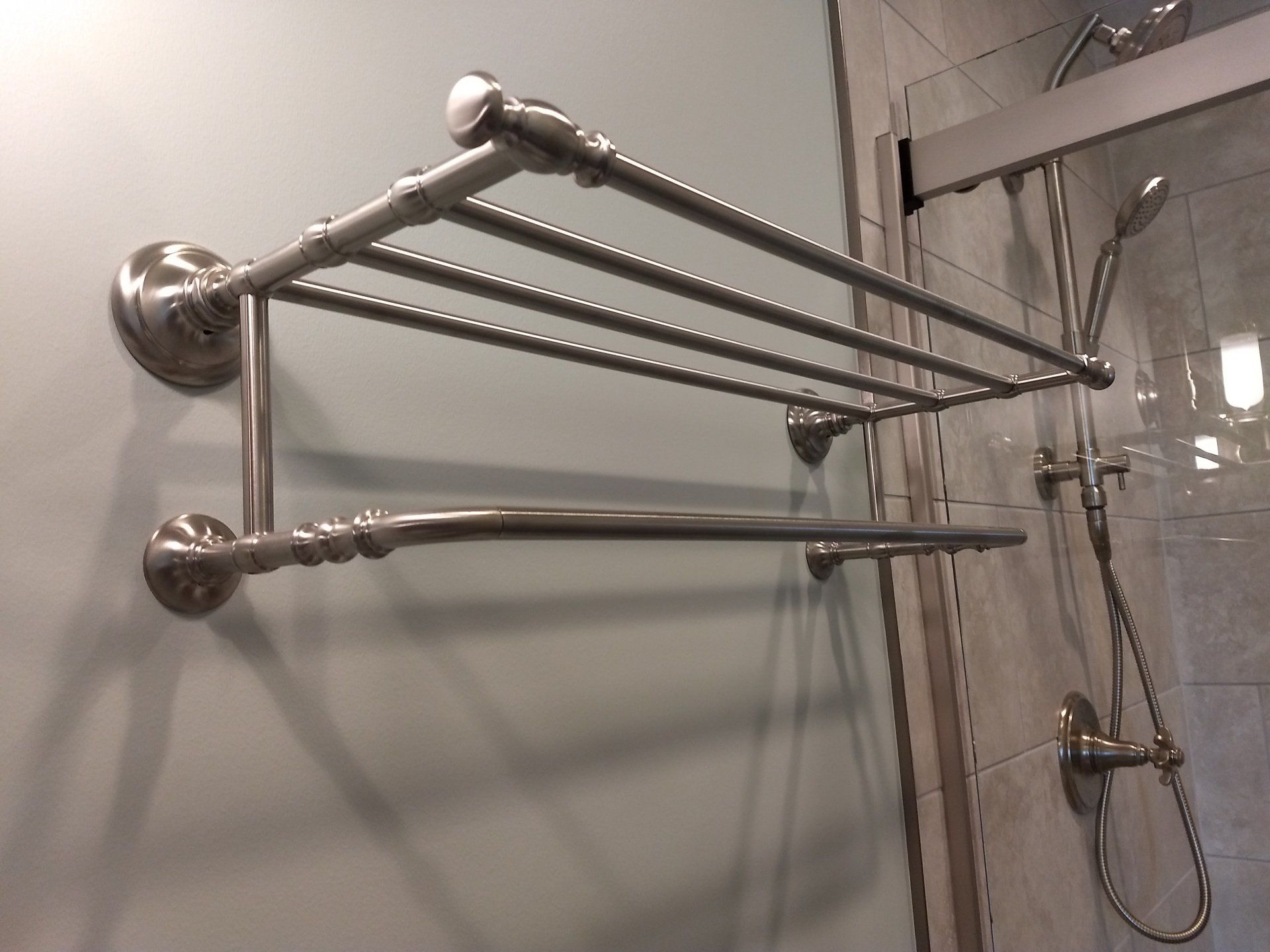 A towel rack in a bathroom next to a shower head