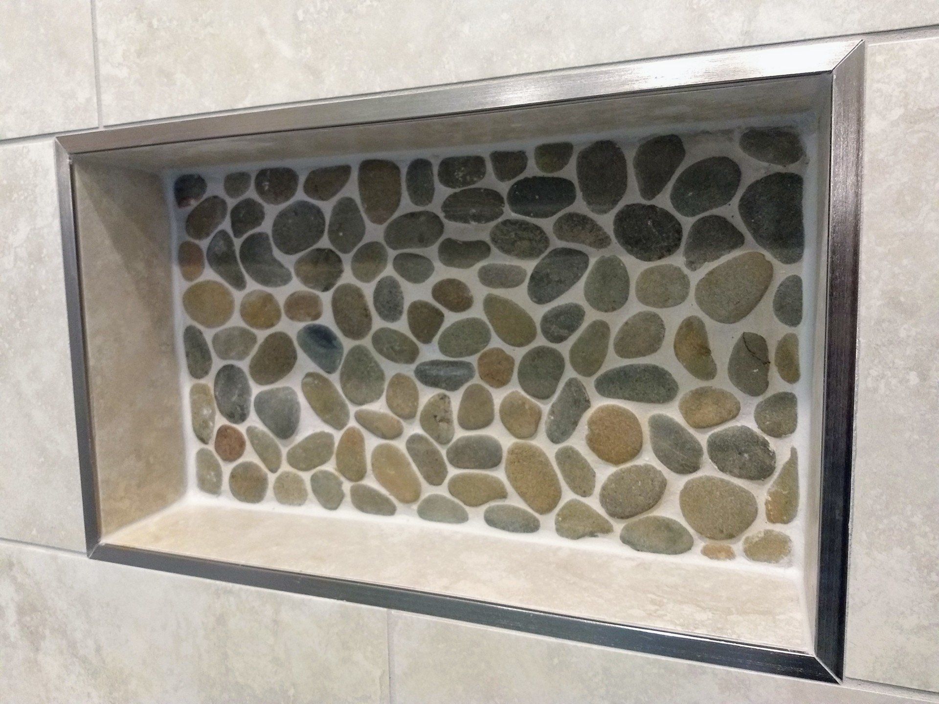 A shower niche with a mosaic of rocks in it