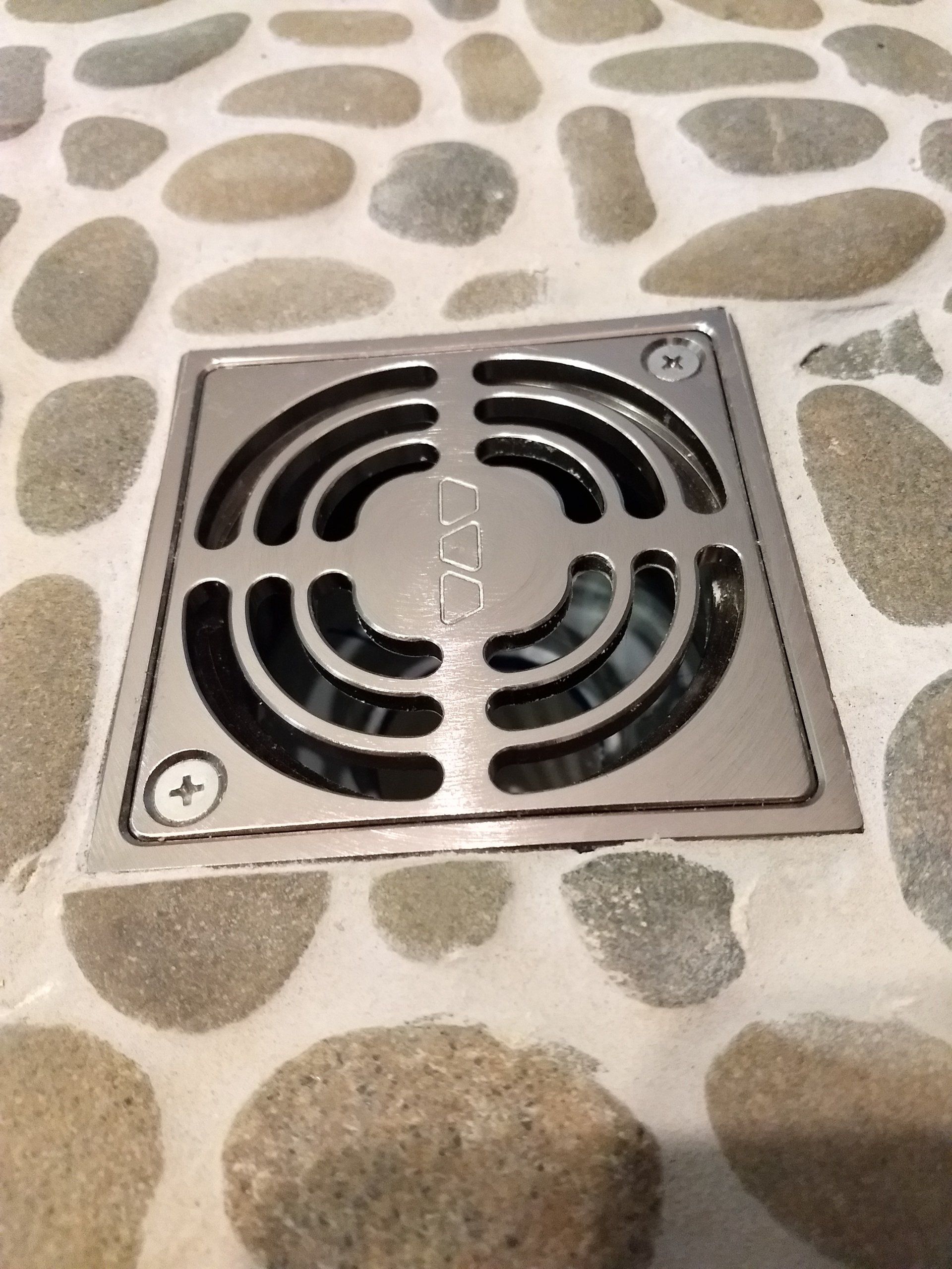 A close up of a drain on a stone floor