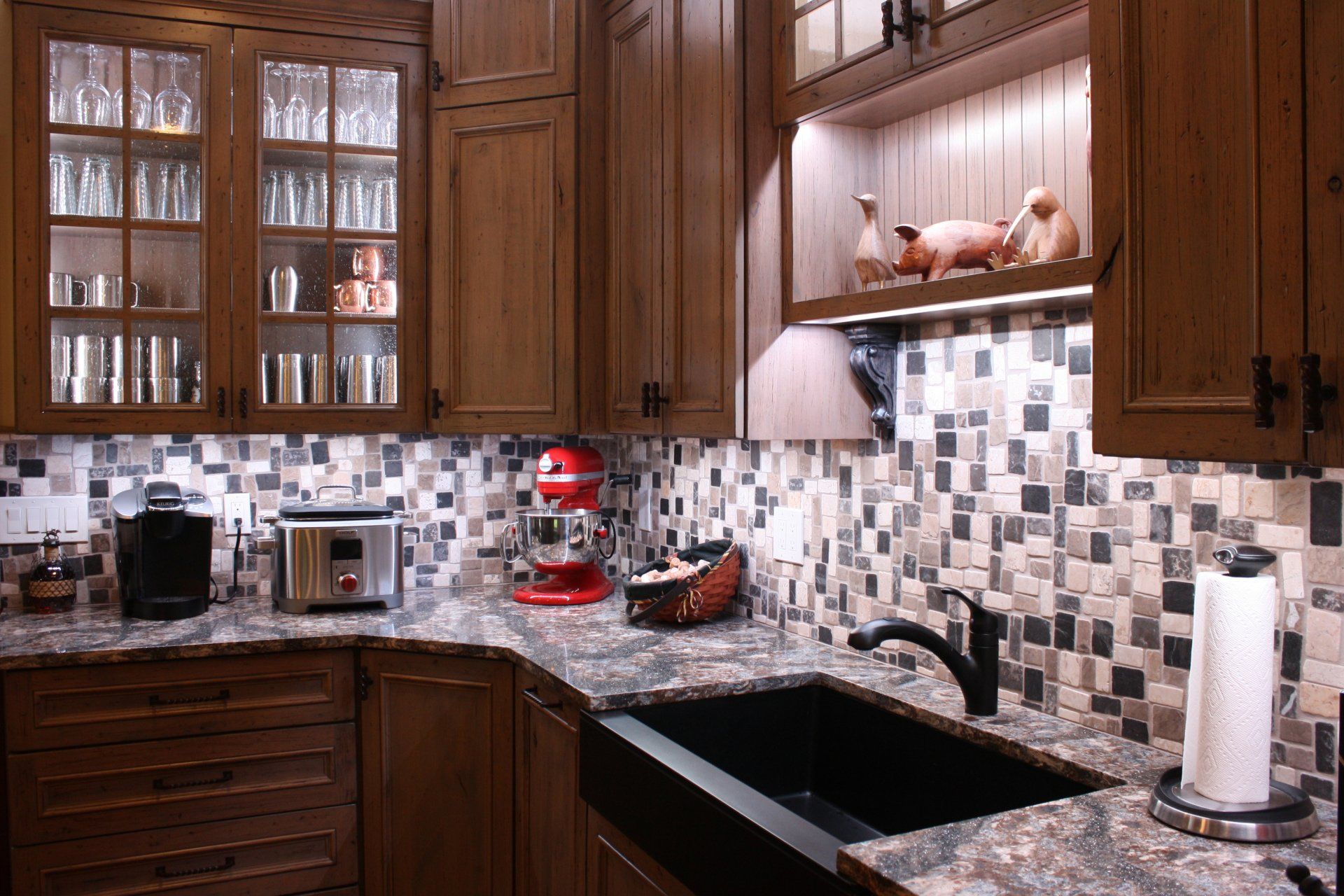 A kitchen with wooden cabinets , granite counter tops , a sink and a toaster oven.