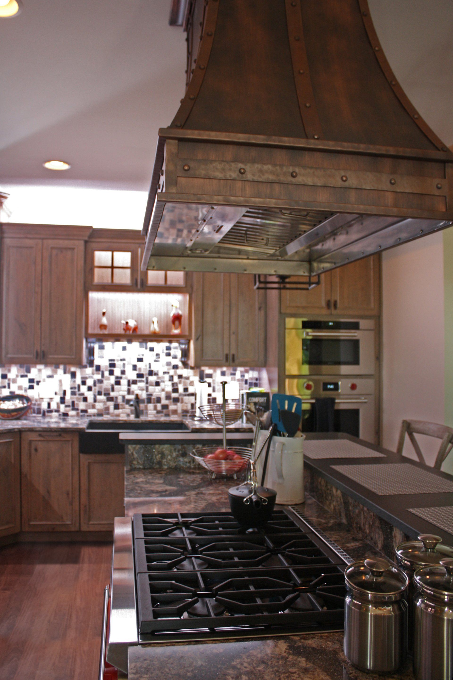 A kitchen with a stove top oven and a wooden hood.
