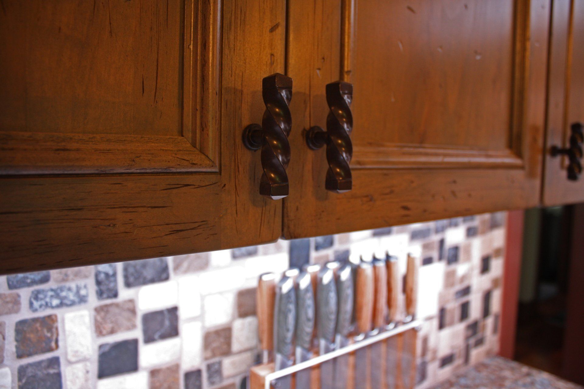 A kitchen with wooden cabinets and knives on a shelf