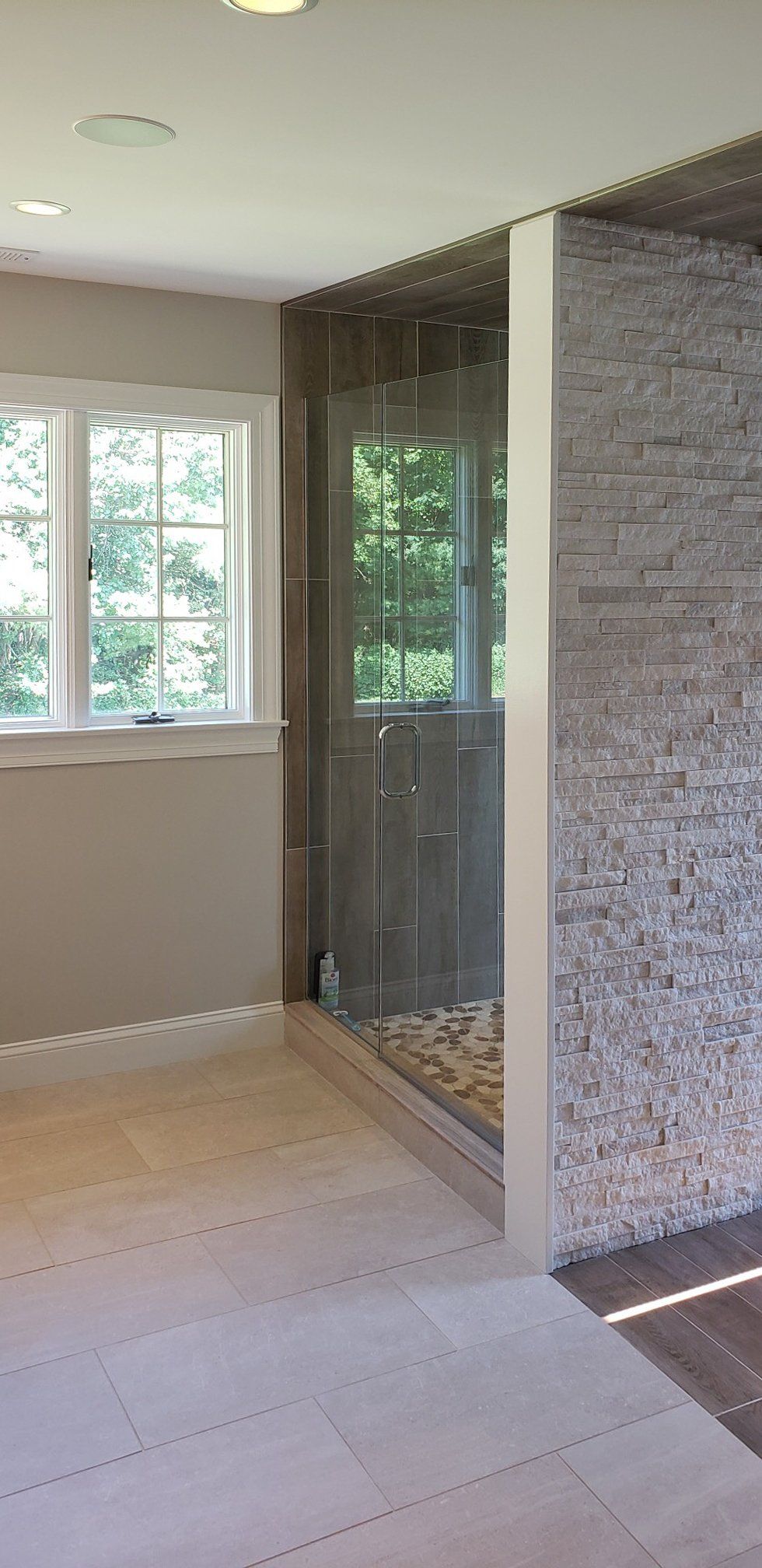 A bathroom with a walk in shower and a window.