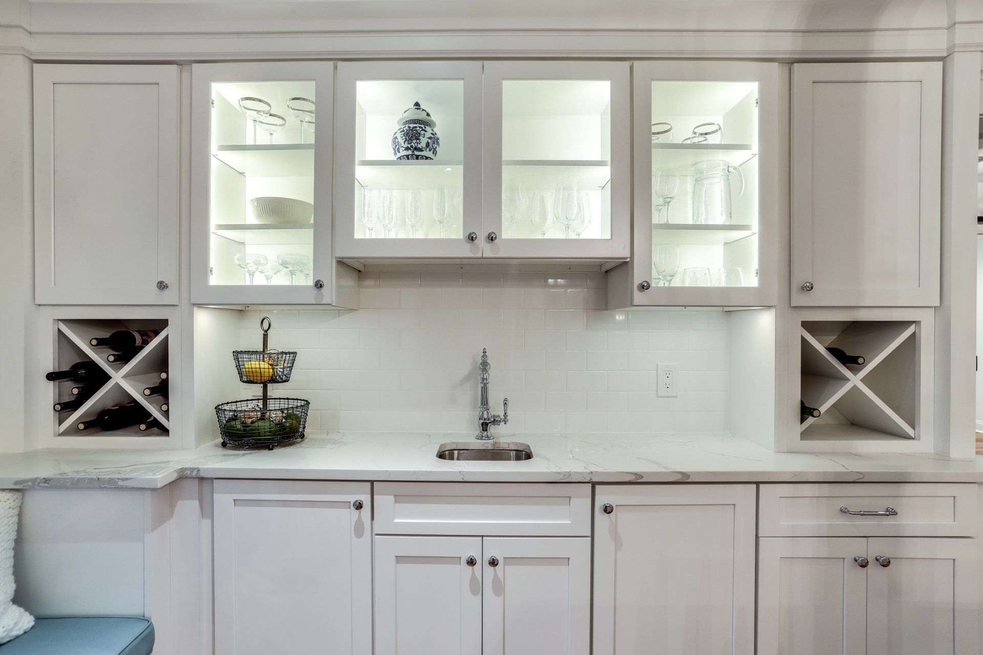 A kitchen with white cabinets , a sink , and a wine rack.