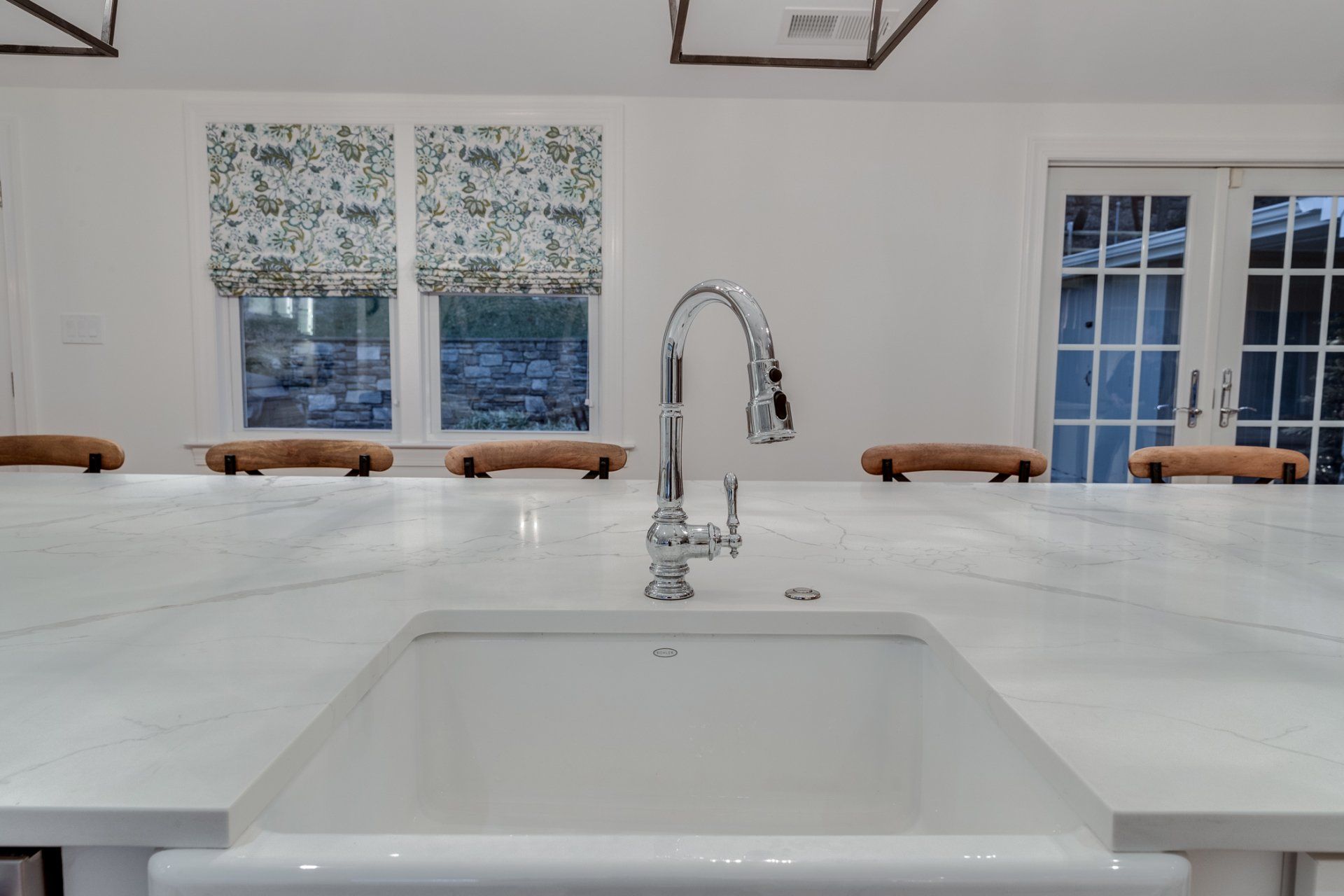 A kitchen sink with a faucet and a marble counter top.