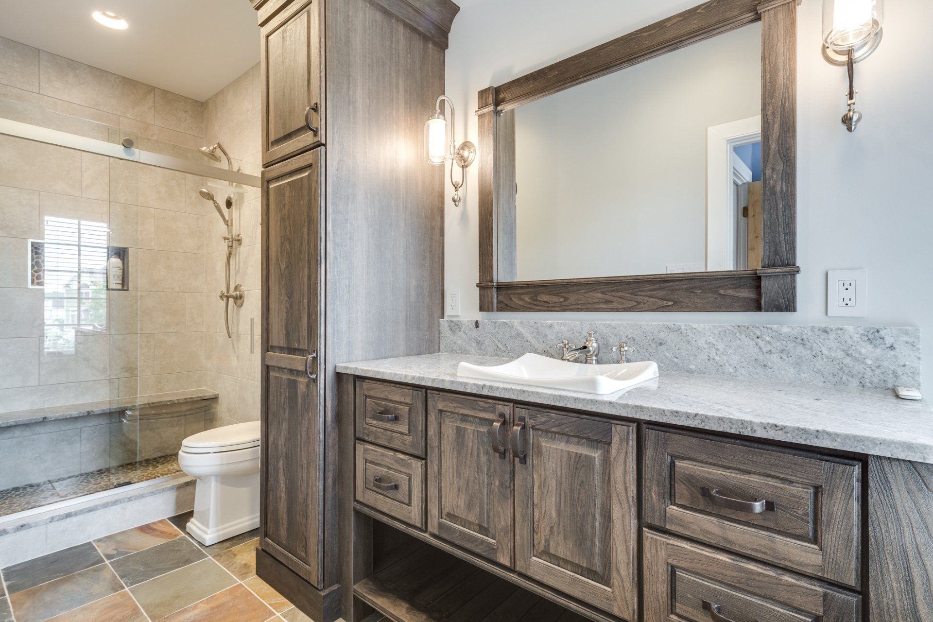 A bathroom with a sink , toilet , shower and mirror.