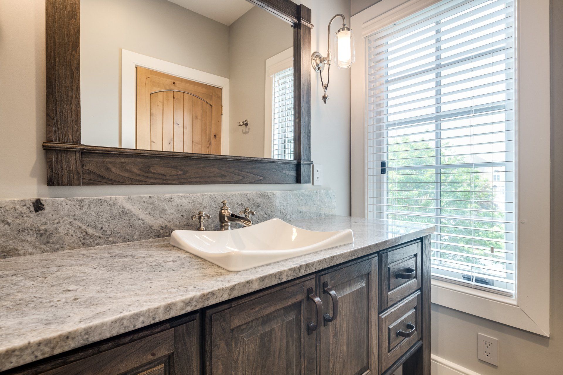 A bathroom with a sink , mirror and window.