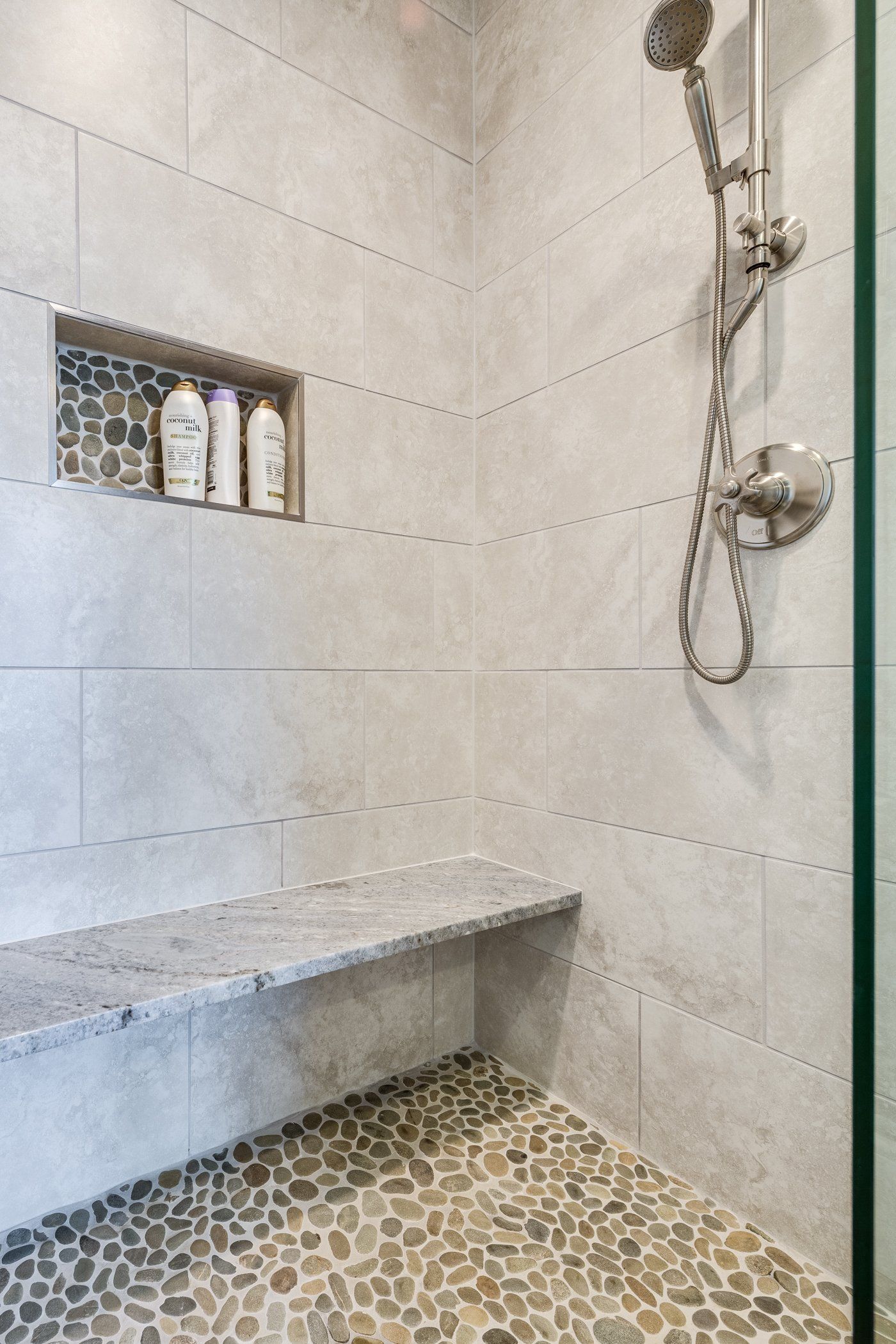 A shower with a bench and a shower head.