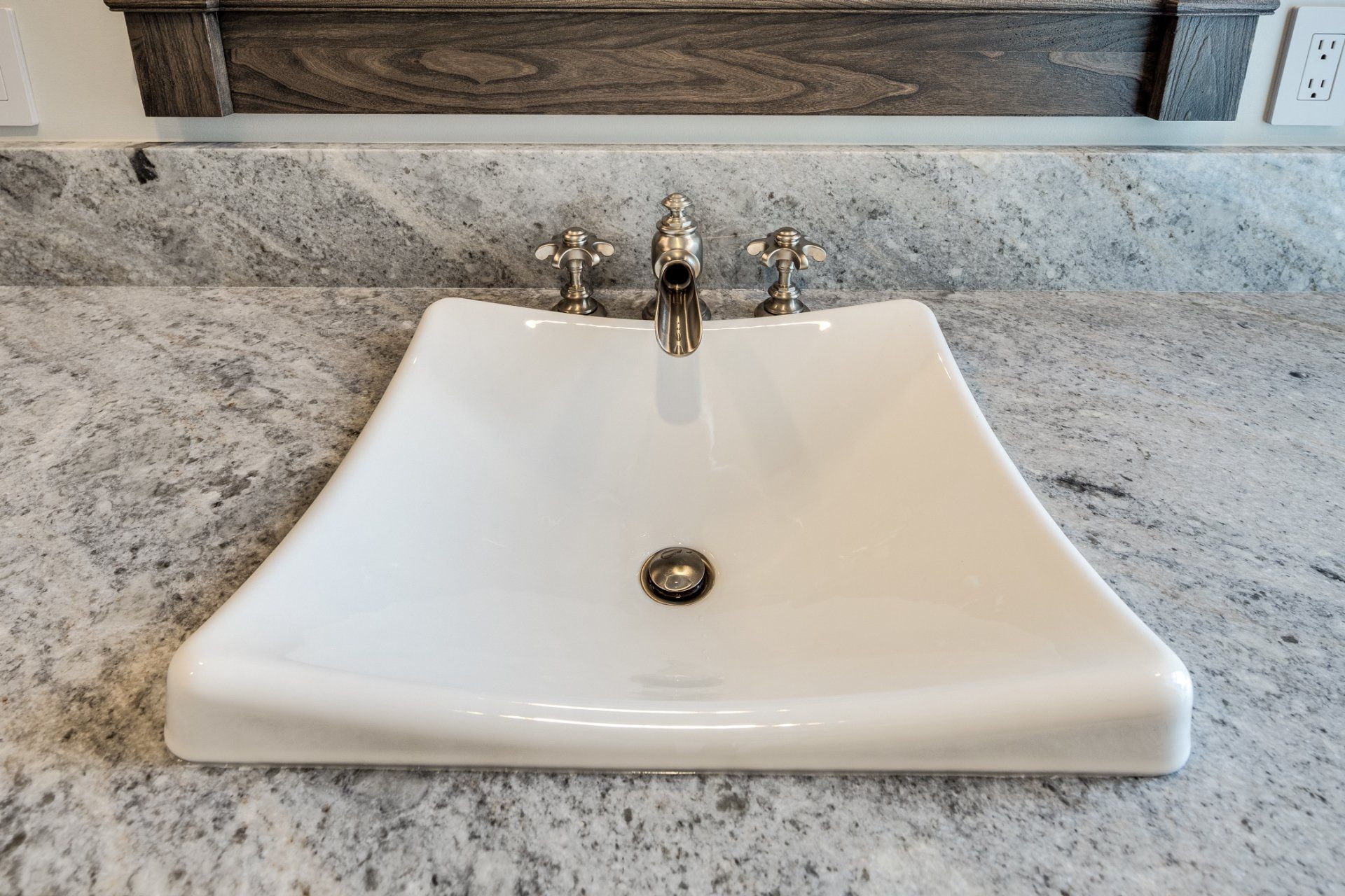 A bathroom sink with a faucet on a granite counter top.