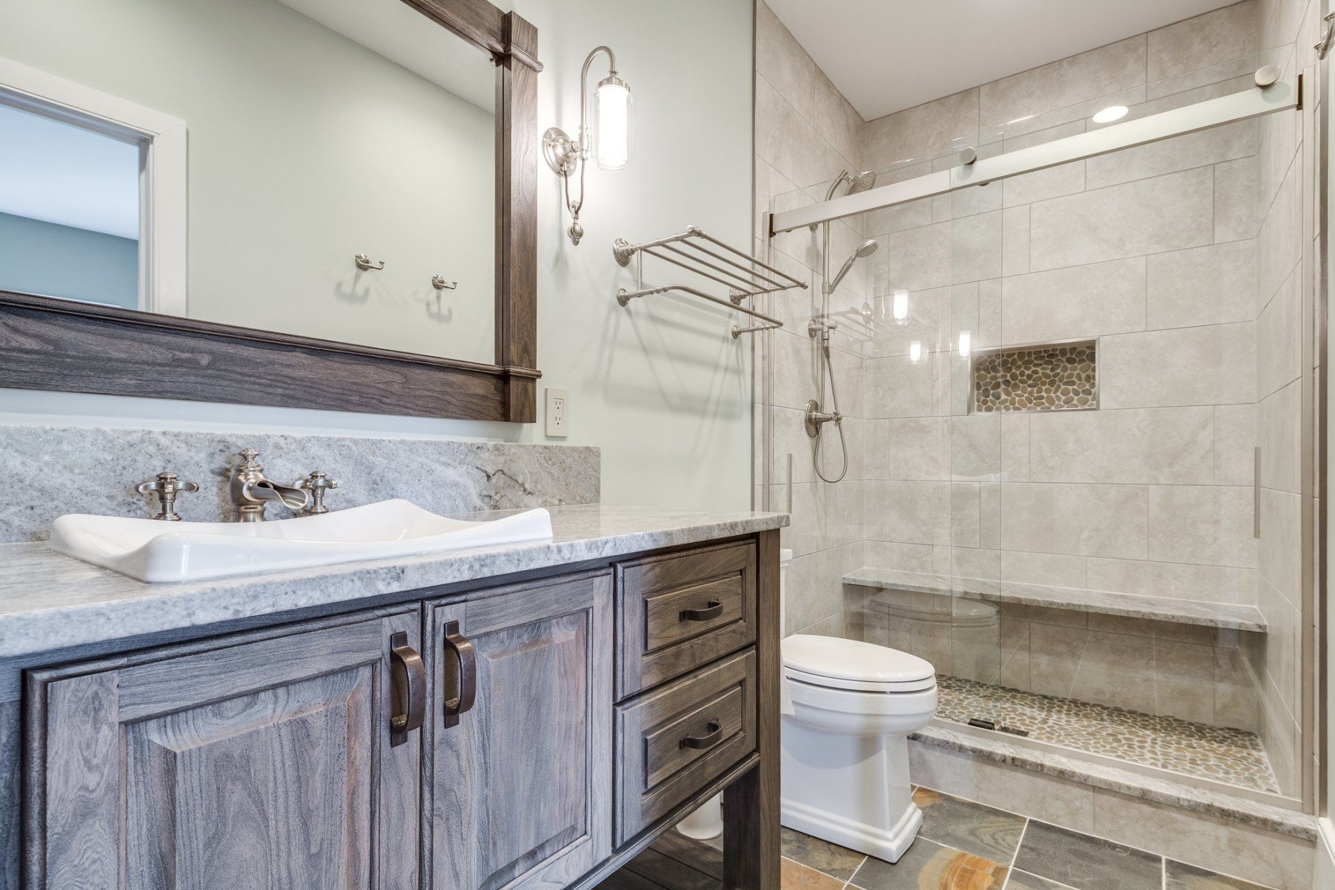 A bathroom with a sink , toilet , shower and mirror.