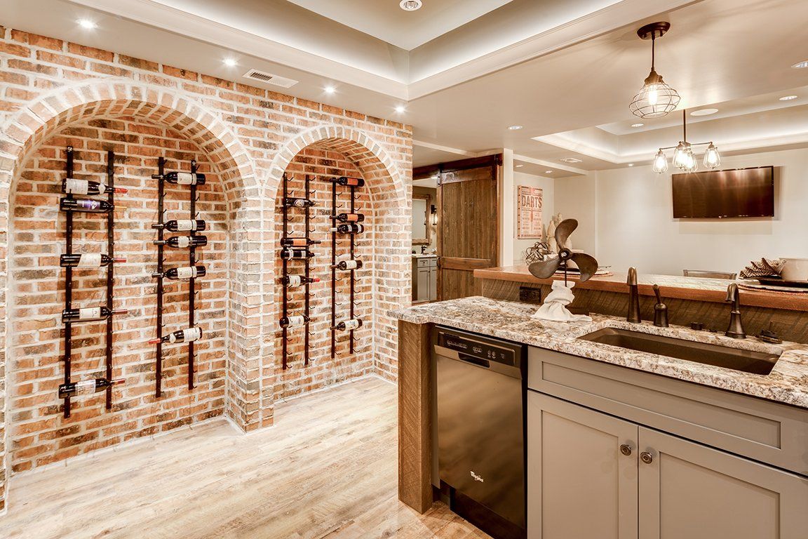 A kitchen with a brick wall and wine racks on the wall.
