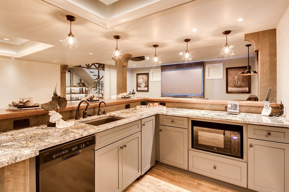 A kitchen with granite counter tops , stainless steel appliances , a sink and a microwave.
