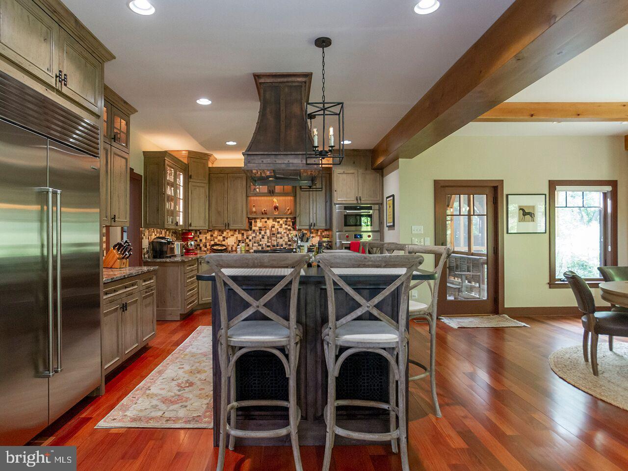 A kitchen with stainless steel appliances , wooden floors , and a large island.