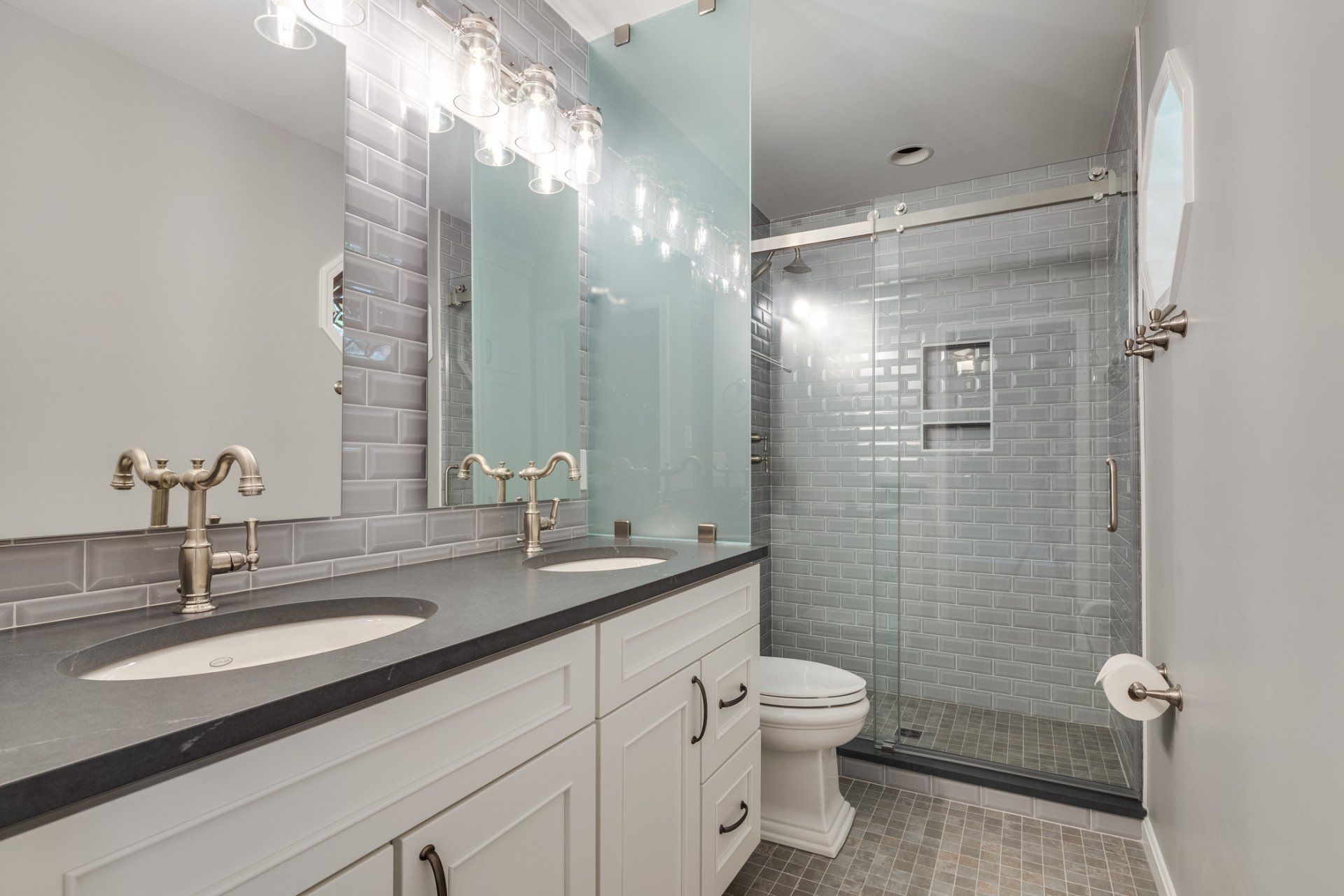 A bathroom with a toilet , sink , mirror and walk in shower.