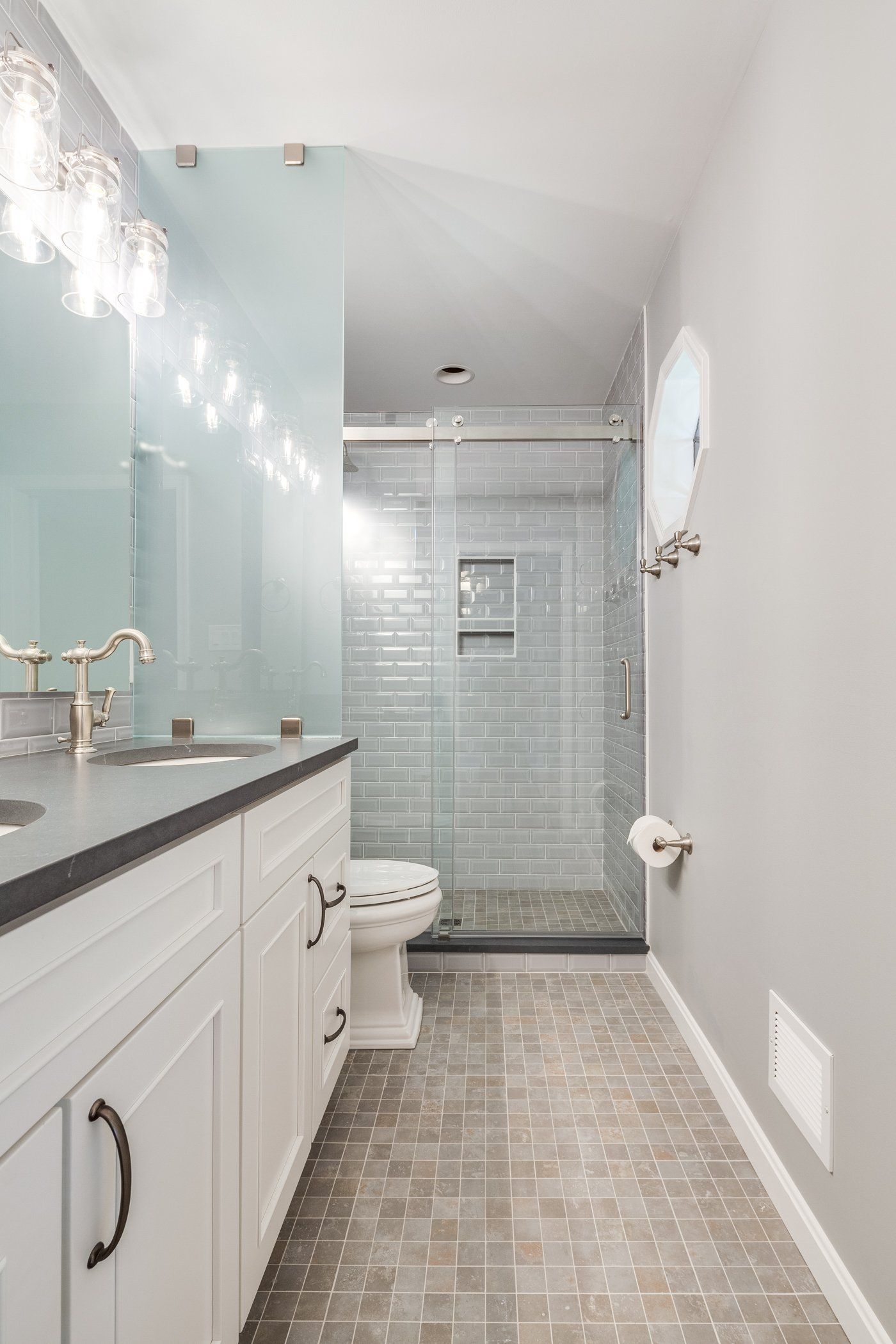 A bathroom with a toilet , sink , mirror and walk in shower.