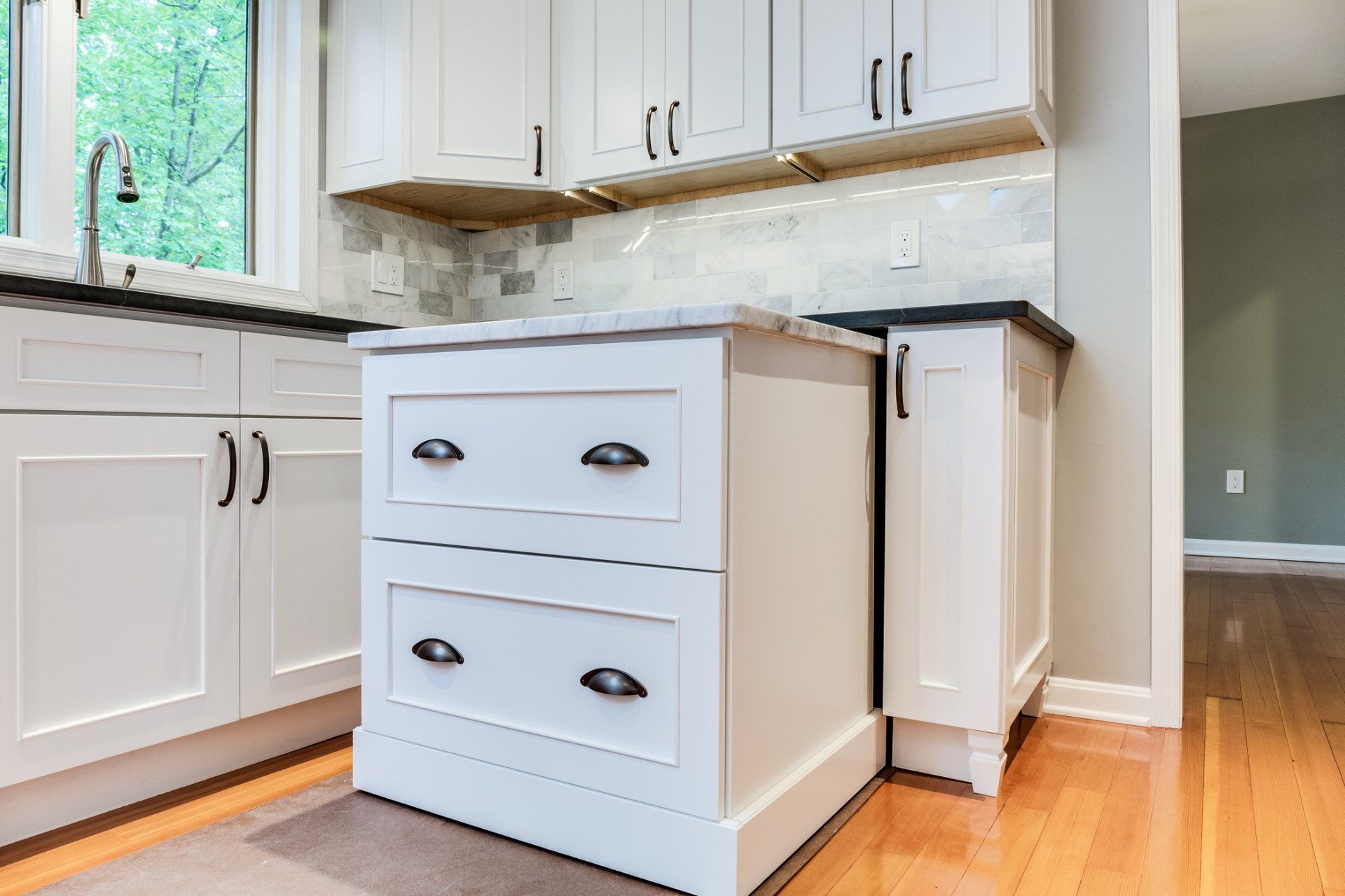 A kitchen with white cabinets and black drawers and a sink.