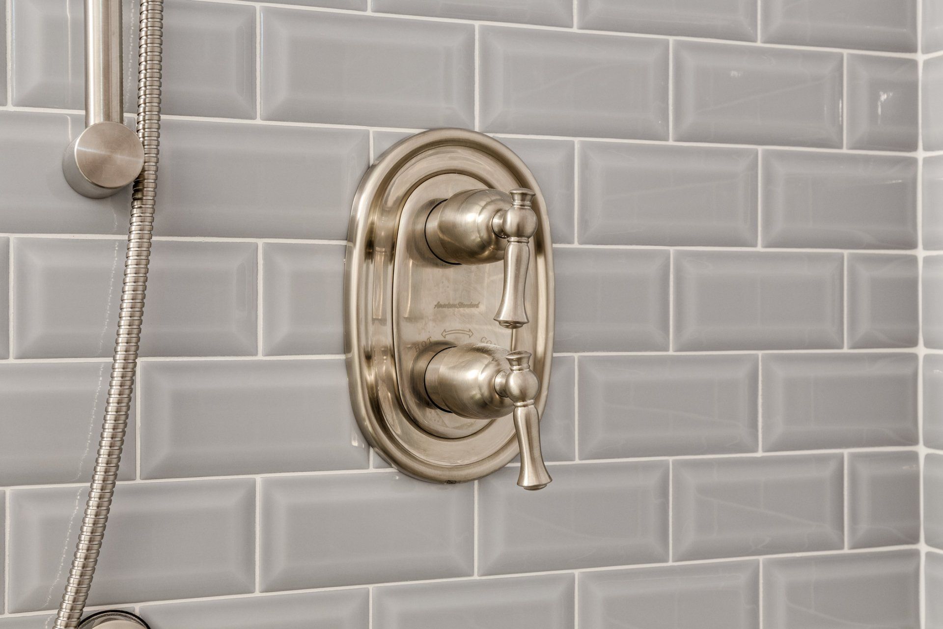 A close up of a shower faucet on a gray brick wall.