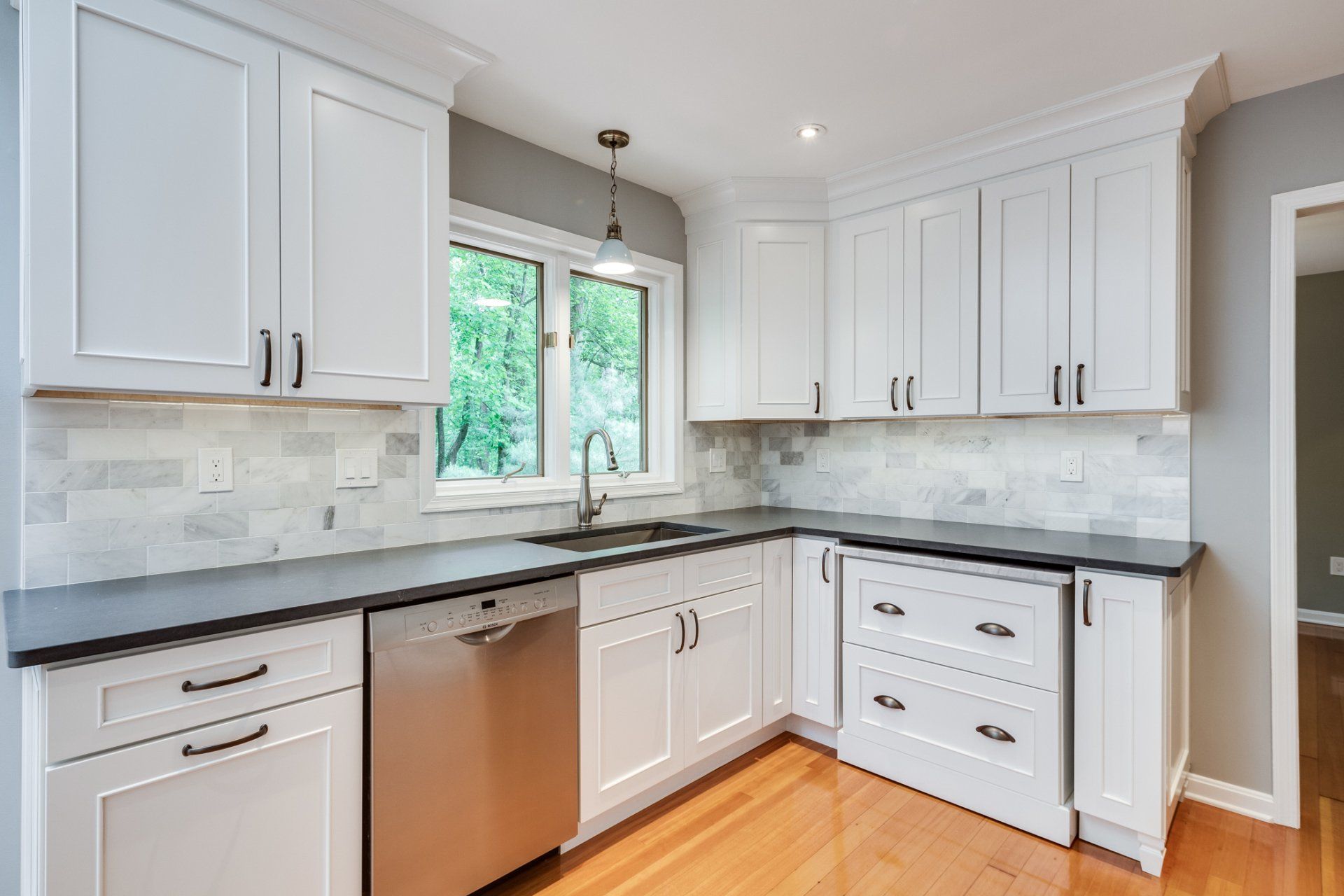 A kitchen with white cabinets , black counter tops , and stainless steel appliances.