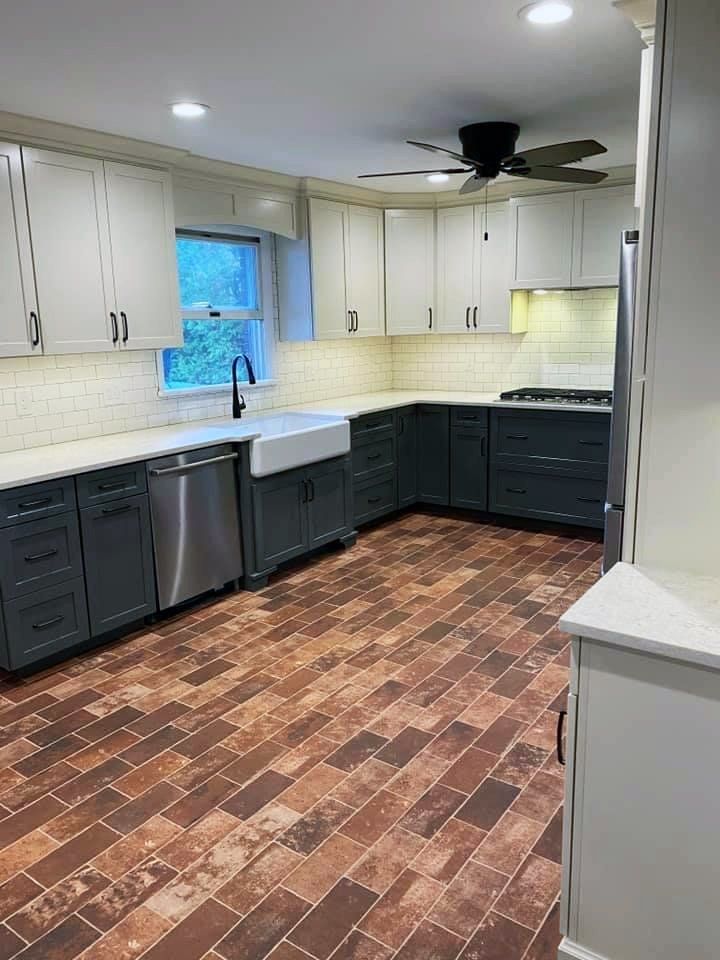 A kitchen with stainless steel appliances , a sink , and a ceiling fan.