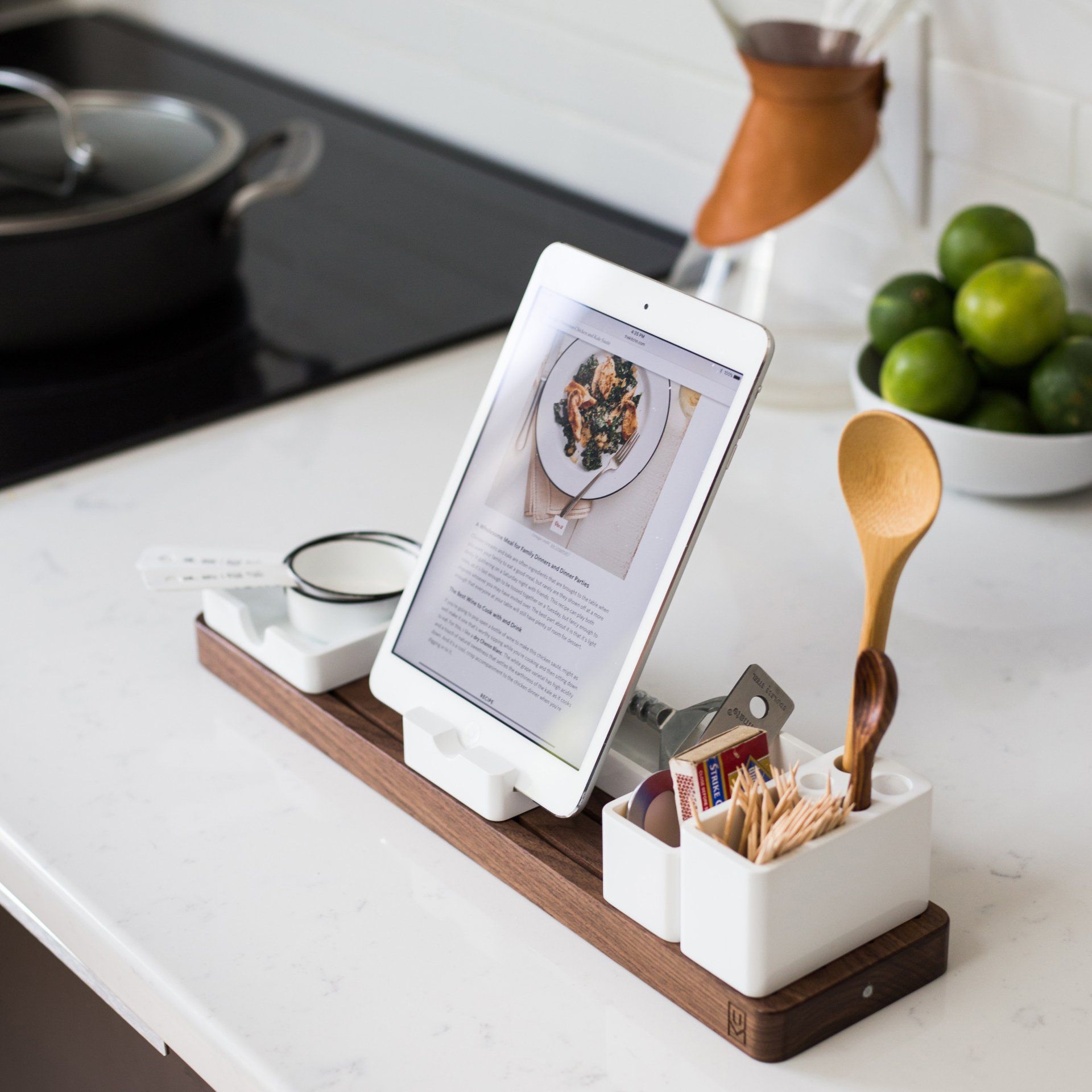 A tablet is sitting on a wooden tray on a kitchen counter