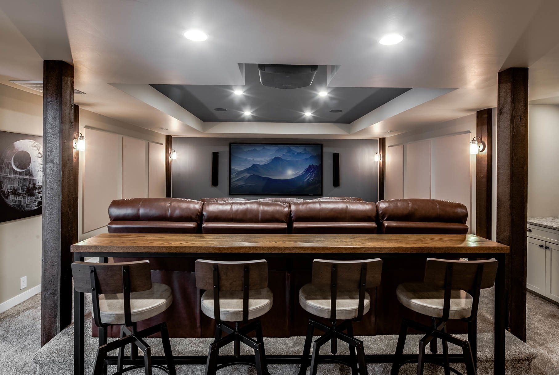 A home theater with a couch , bar , chairs and a flat screen tv.
