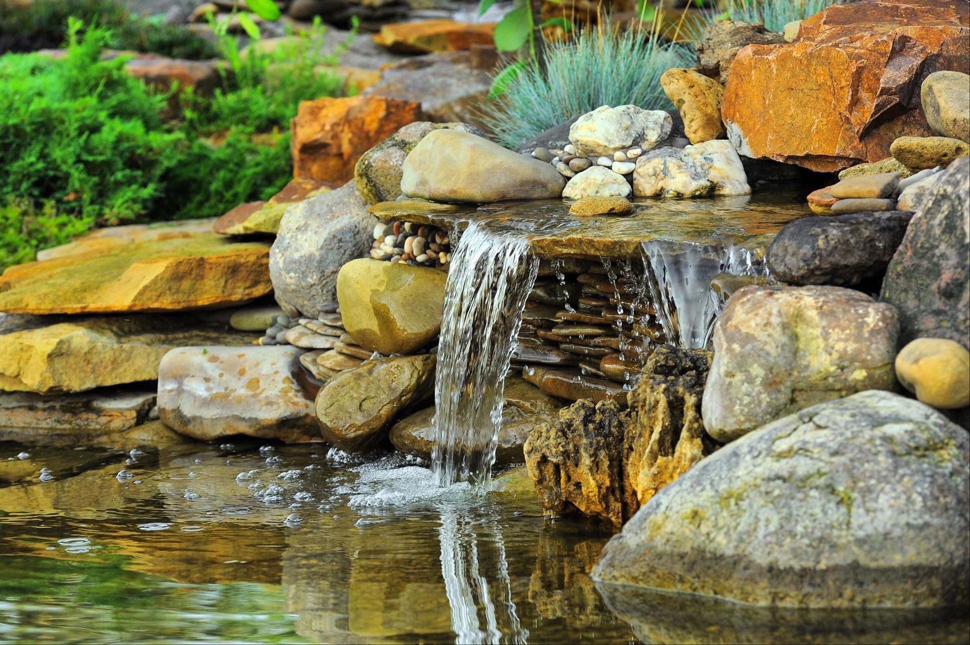 Small Waterfall is Surrounded by Rocks in a Pond