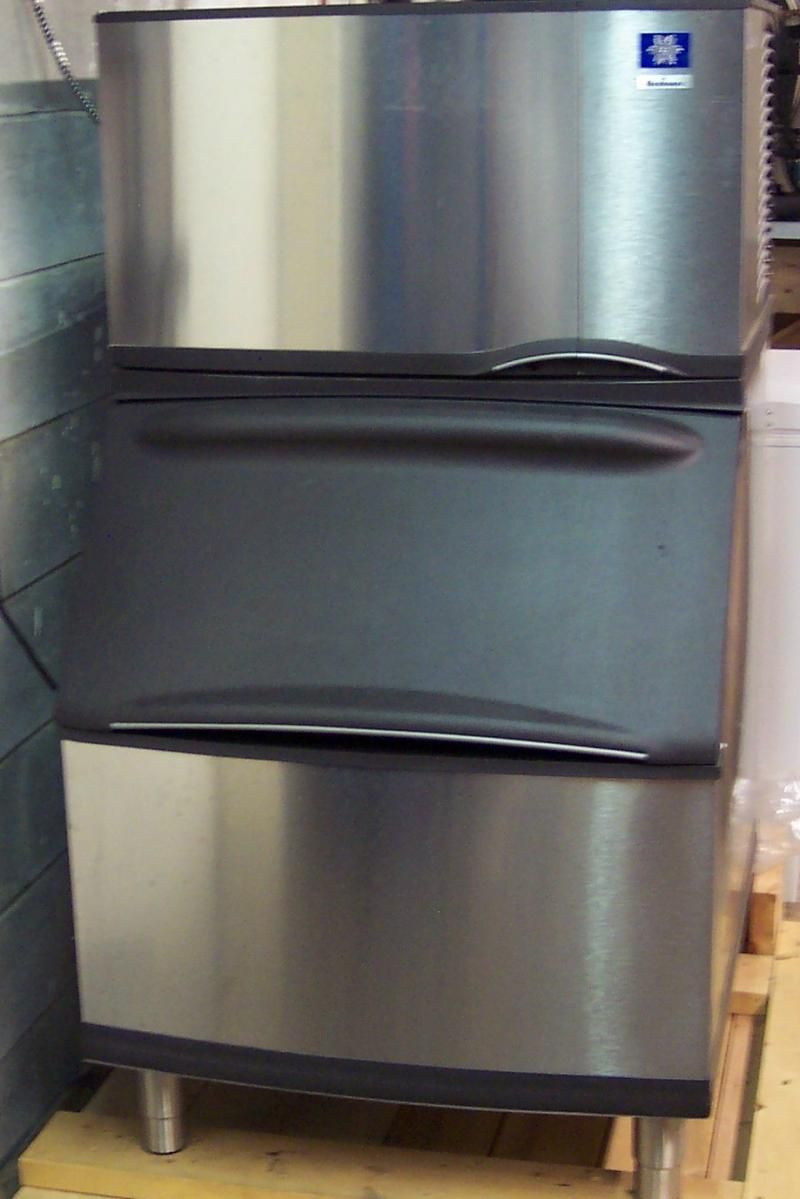 A stainless steel refrigerator is sitting on a wooden floor.