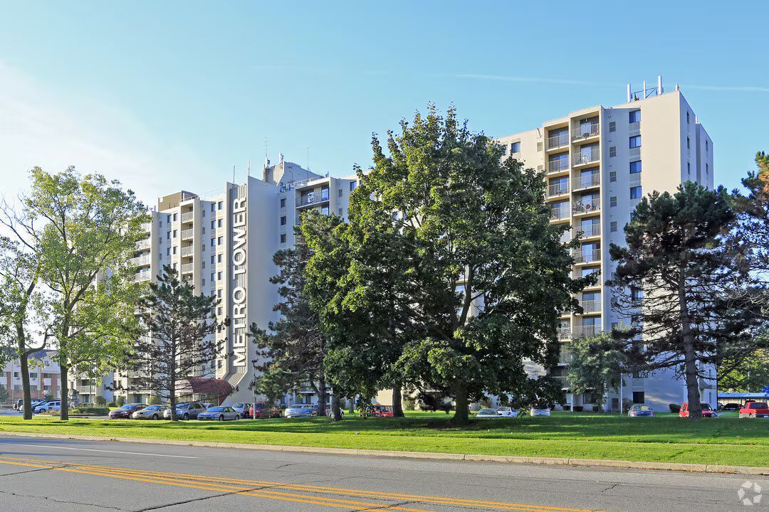A large building with a lot of windows is surrounded by trees and grass.