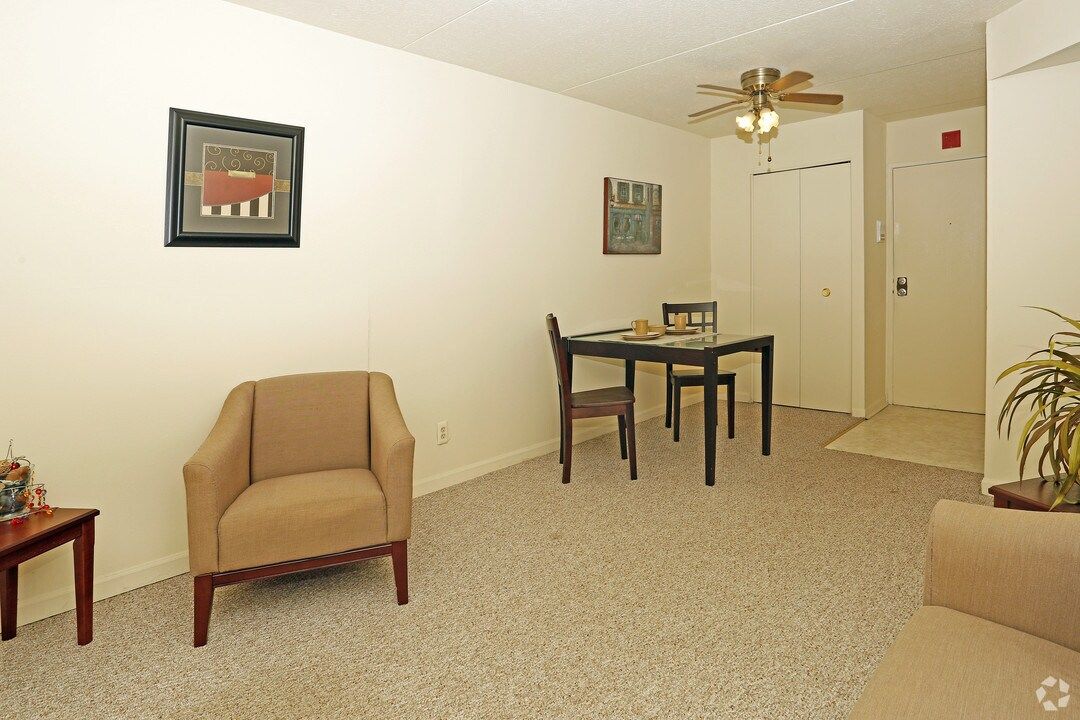A living room with a chair a table and a ceiling fan