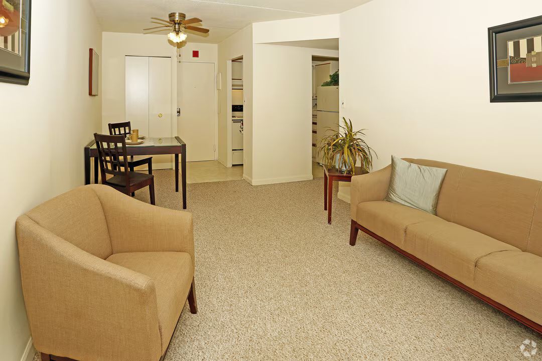 A living room with a couch , chair , table and ceiling fan.