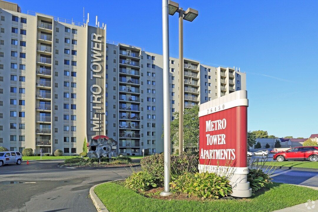 A large apartment building with a sign in front of it that says metro tower apartments.