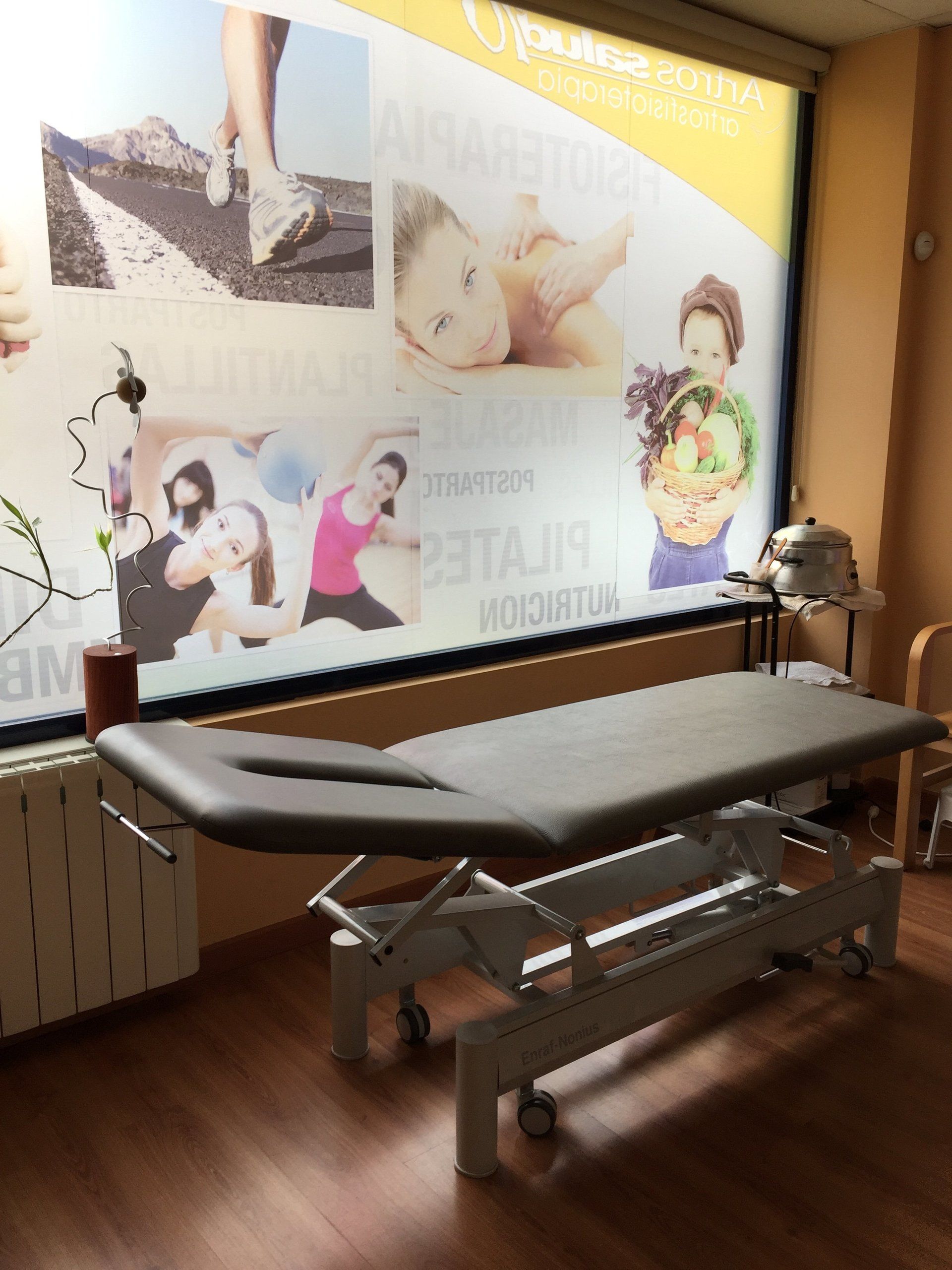 Una mesa de masajes en una habitación con una ventana grande.