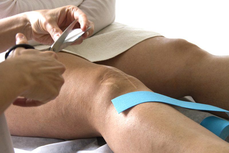 Una persona se aplica cinta kinesiológica en la rodilla.