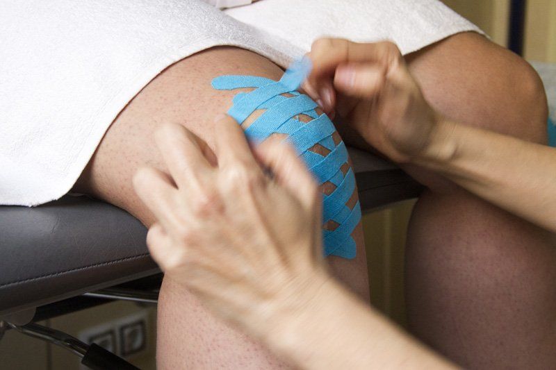 Una persona se aplica cinta kinesiológica en la rodilla.