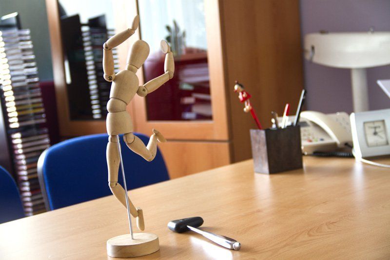 Un maniquí de madera está sentado en un escritorio junto a un martillo.