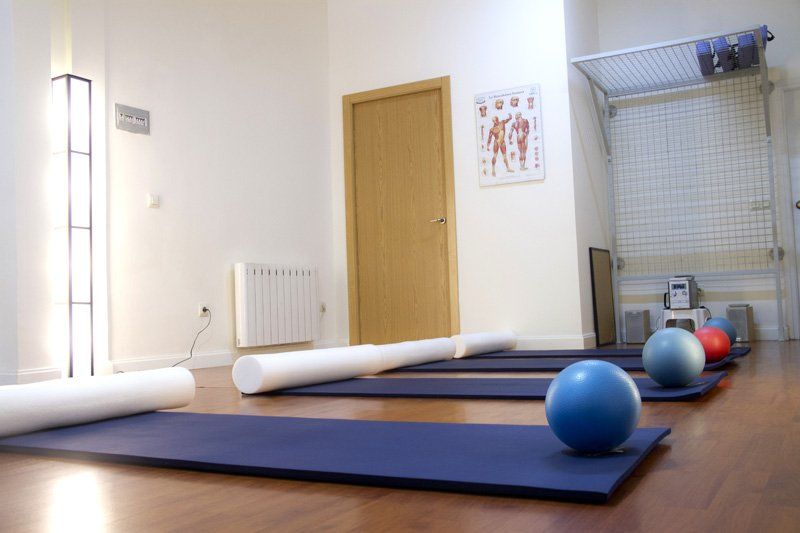 Una sala con colchonetas de pilates y pelotas en el suelo.