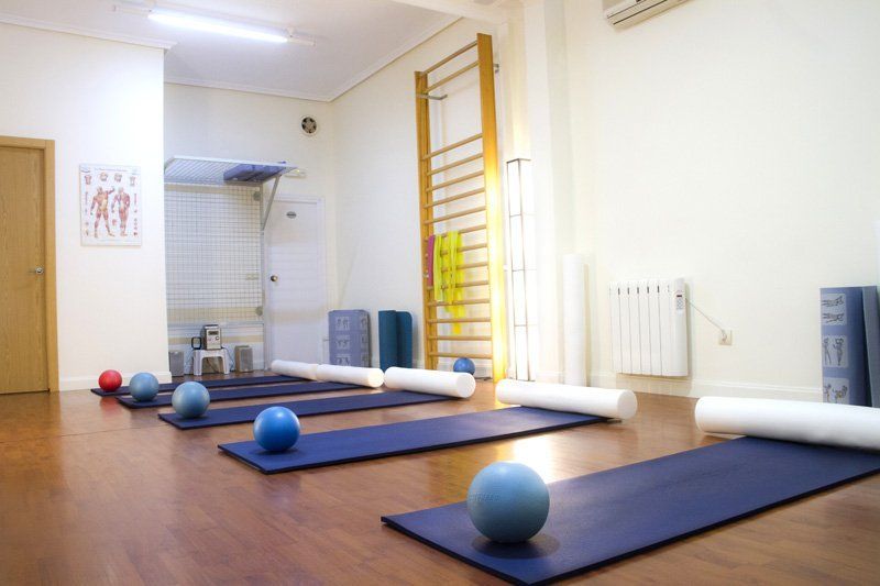 Una habitación con muchas colchonetas y pelotas en el suelo.