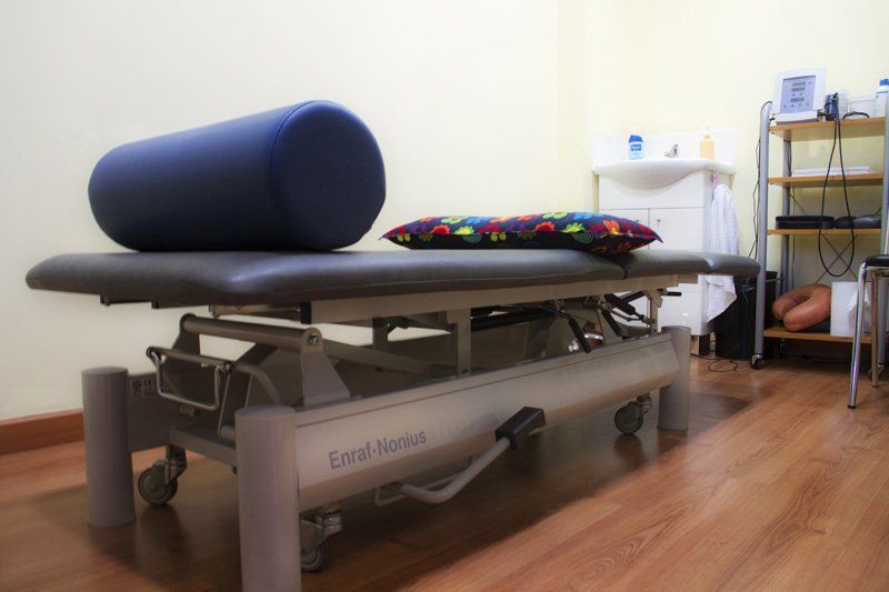 Una mesa de masaje con una almohada azul encima.