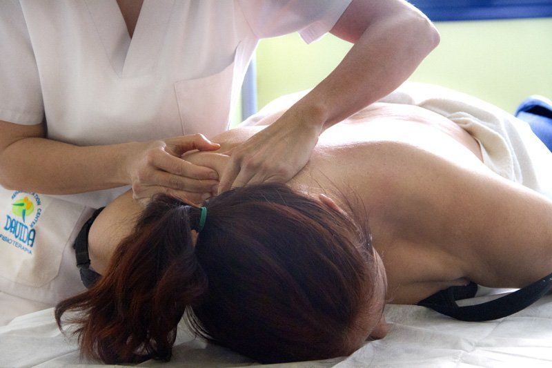 Una mujer está acostada en una cama recibiendo un masaje de una enfermera.