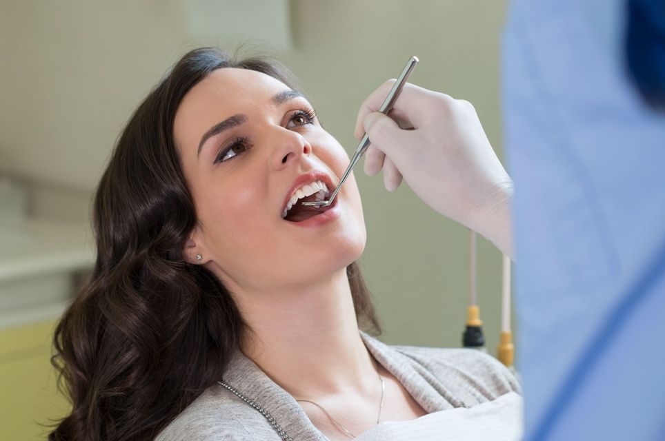 Closeup of dentist examining young woman's teeth