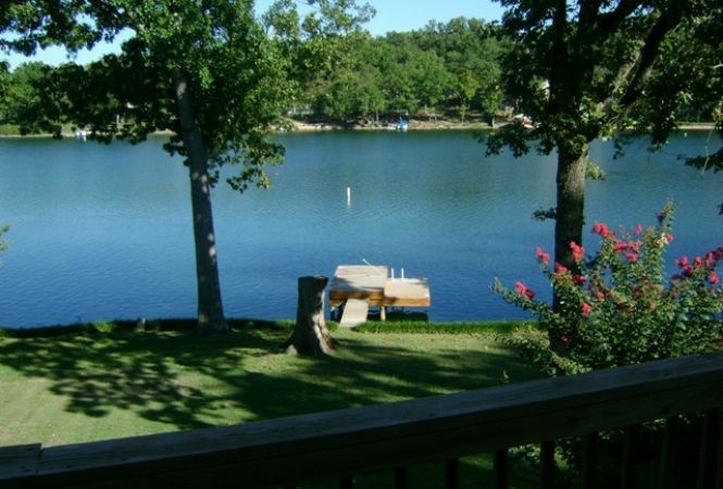 A view of a lake from a deck with a dock in the foreground
