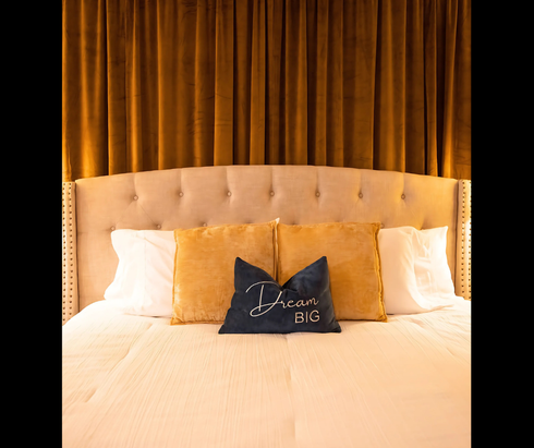 A bed with a headboard and two lamps in a hotel room.