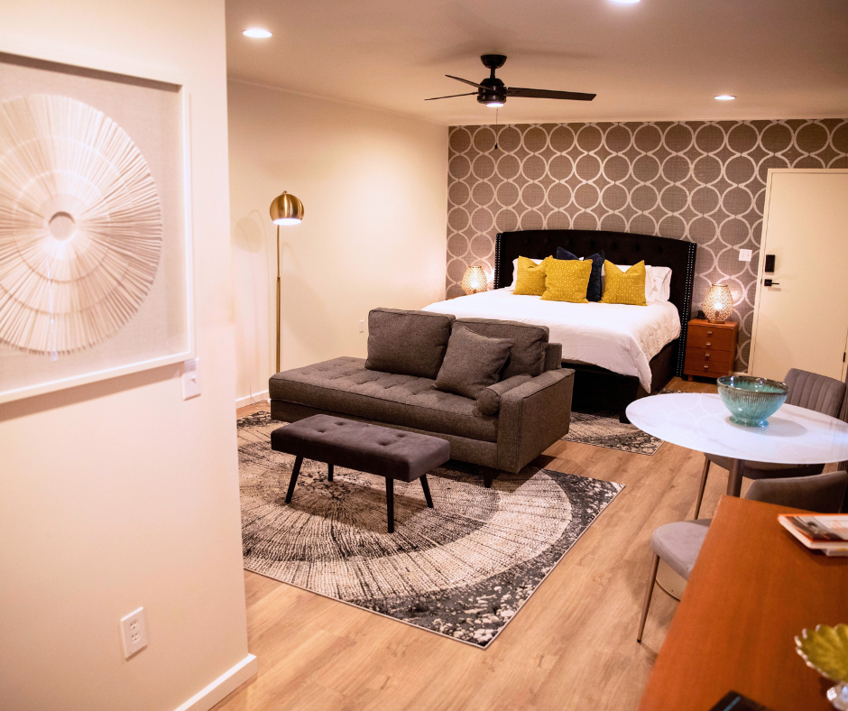 A hotel room with a bed , couch , table and chairs.