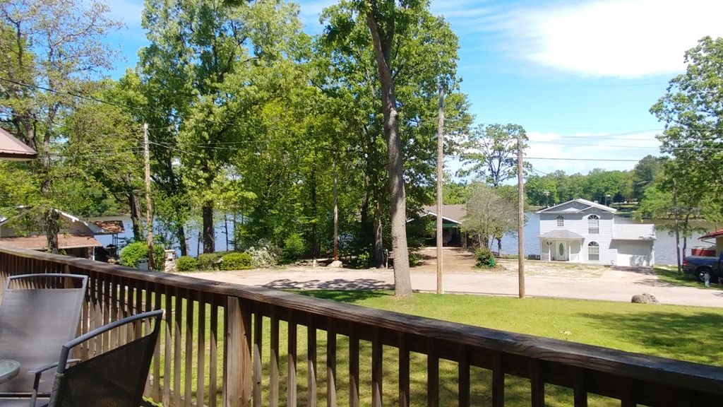 A view of a lake from a deck with a table and chairs.