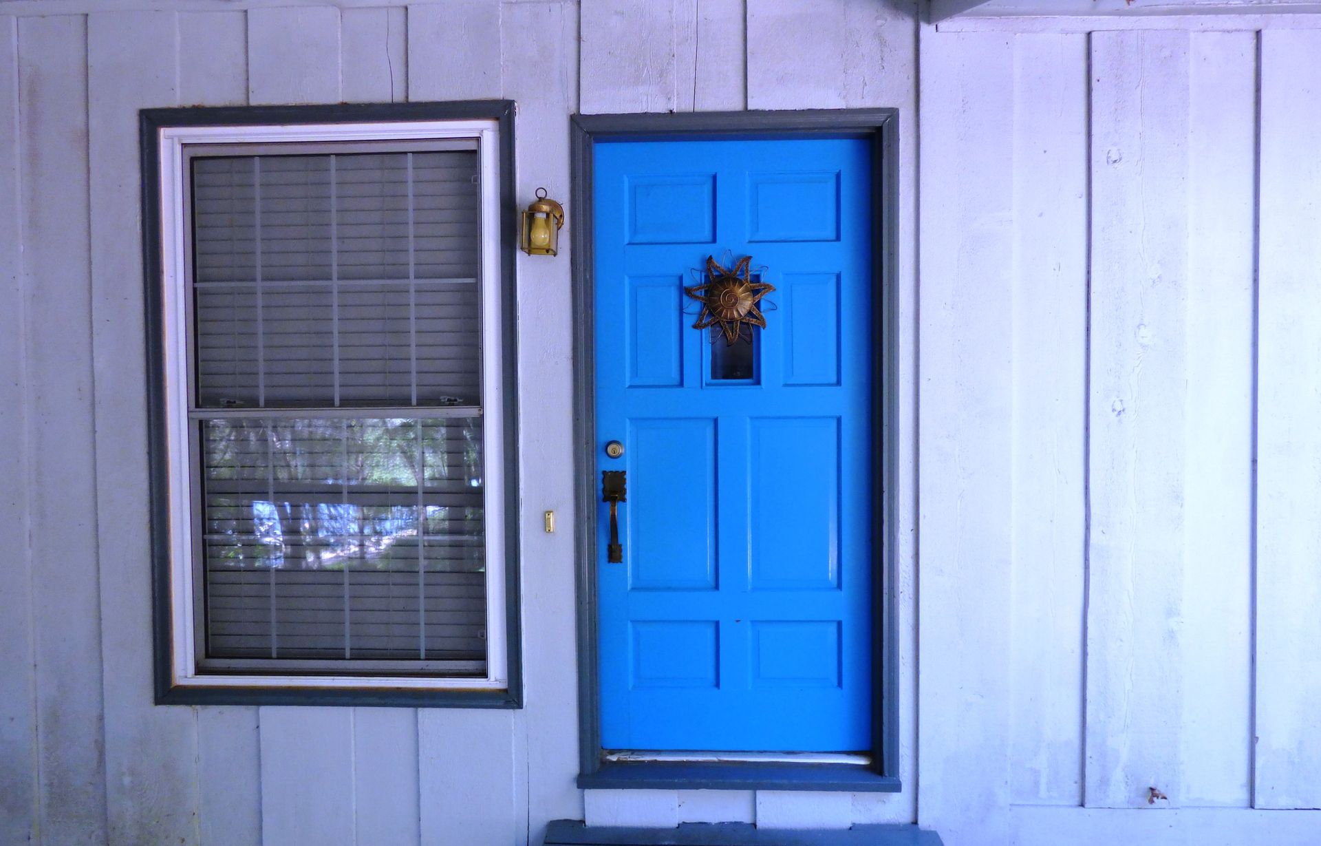 A blue door is next to a window on the side of a house