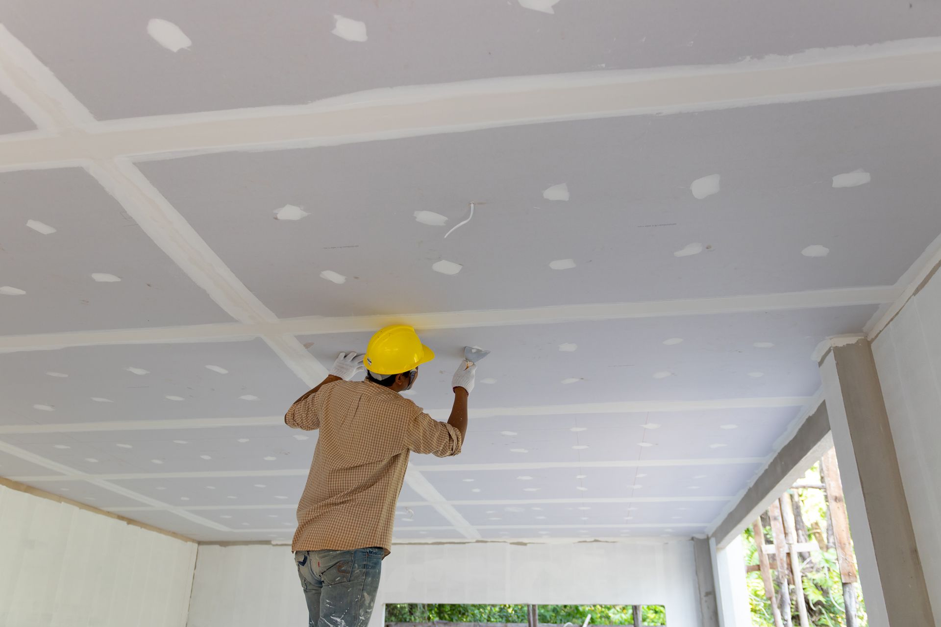 A Man is Working on a Ceiling in a Room