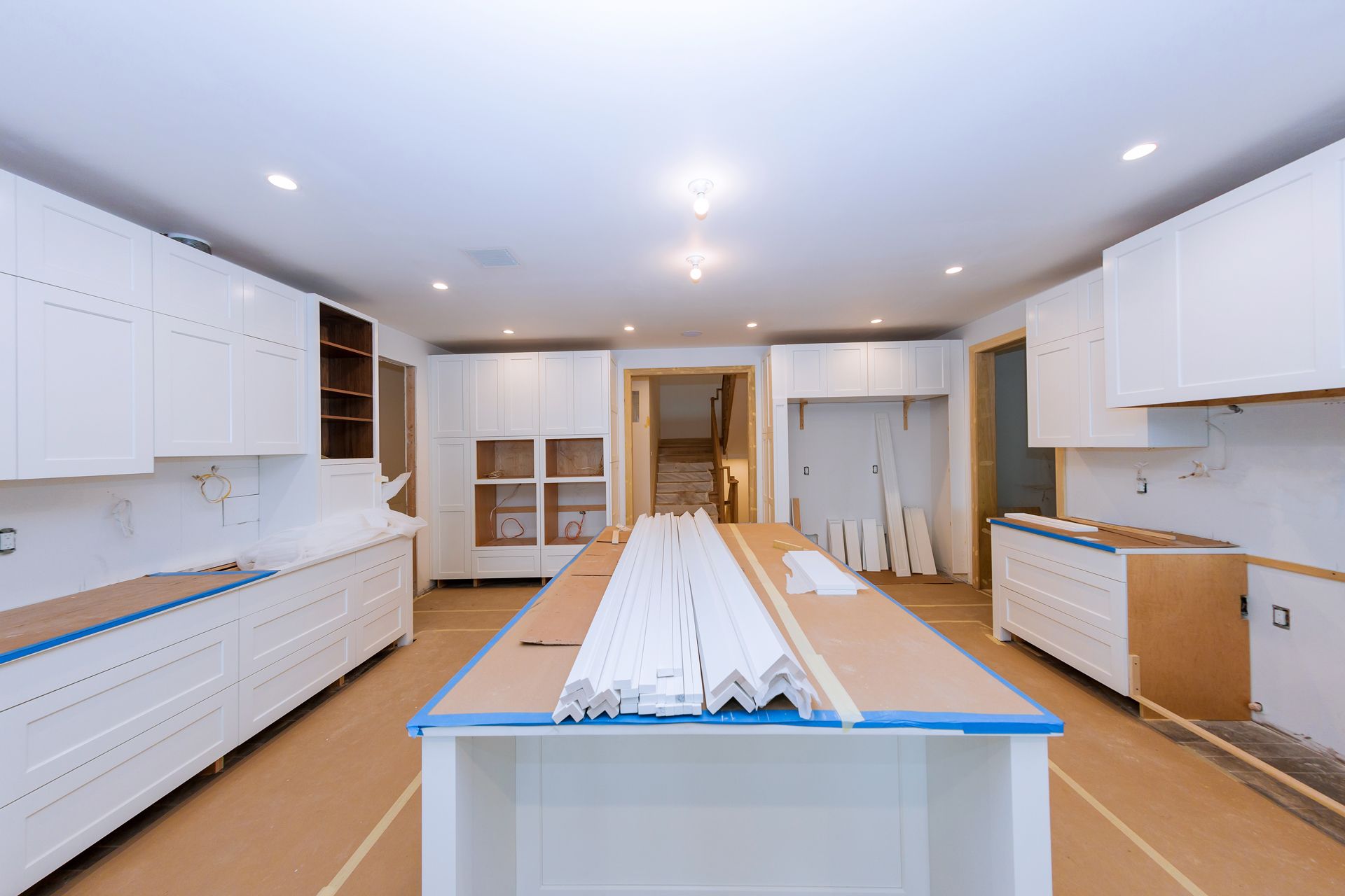 A Kitchen Under Construction With White Cabinets and a Large Island
