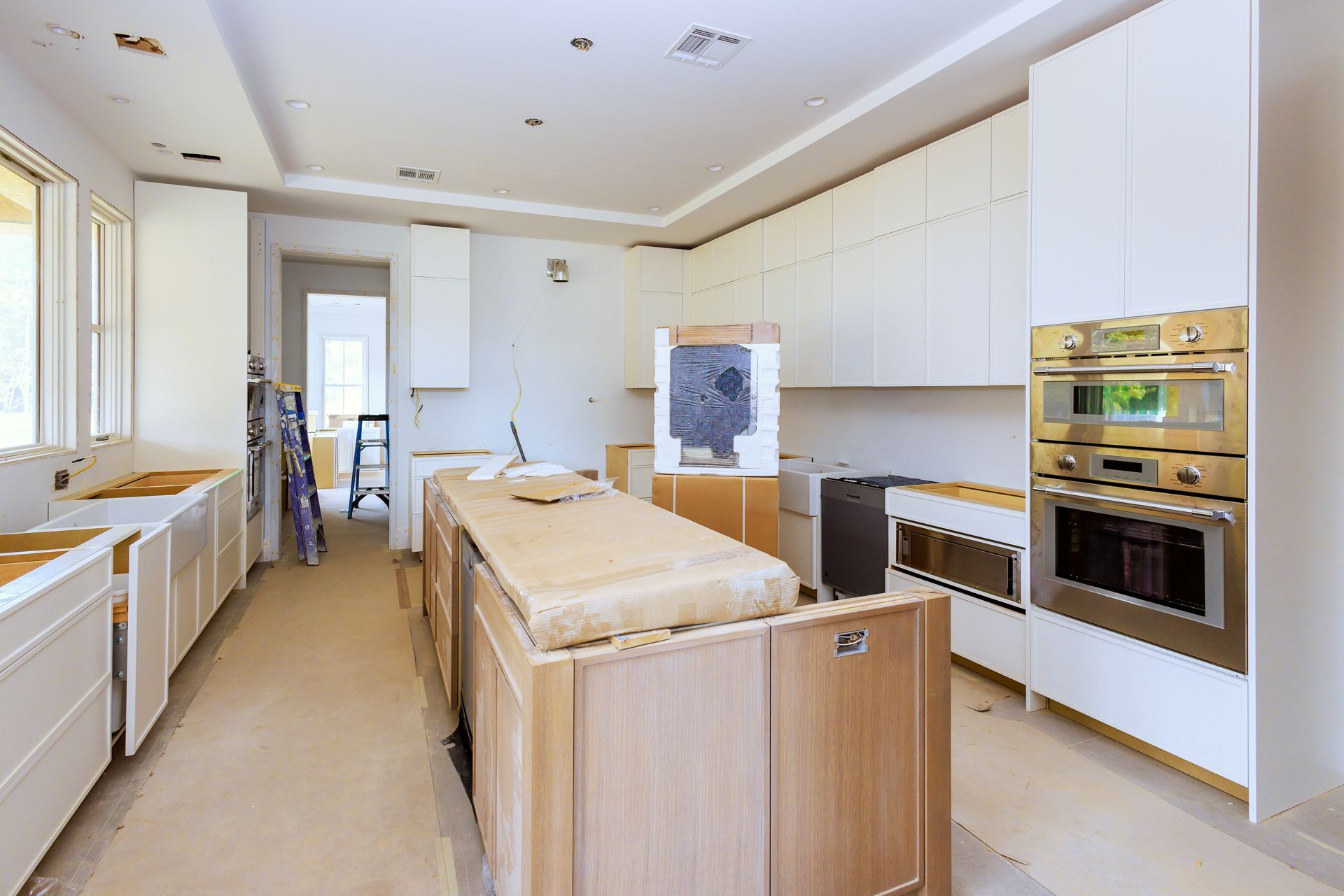 A Kitchen Under Construction With White Cabinets and Stainless Steel Appliances