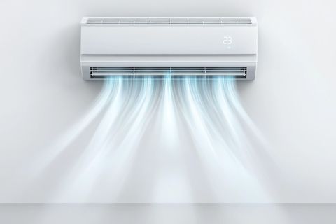A white wall-mounted air conditioner unit blowing a cool mist or breeze downwards against a plain white wall.