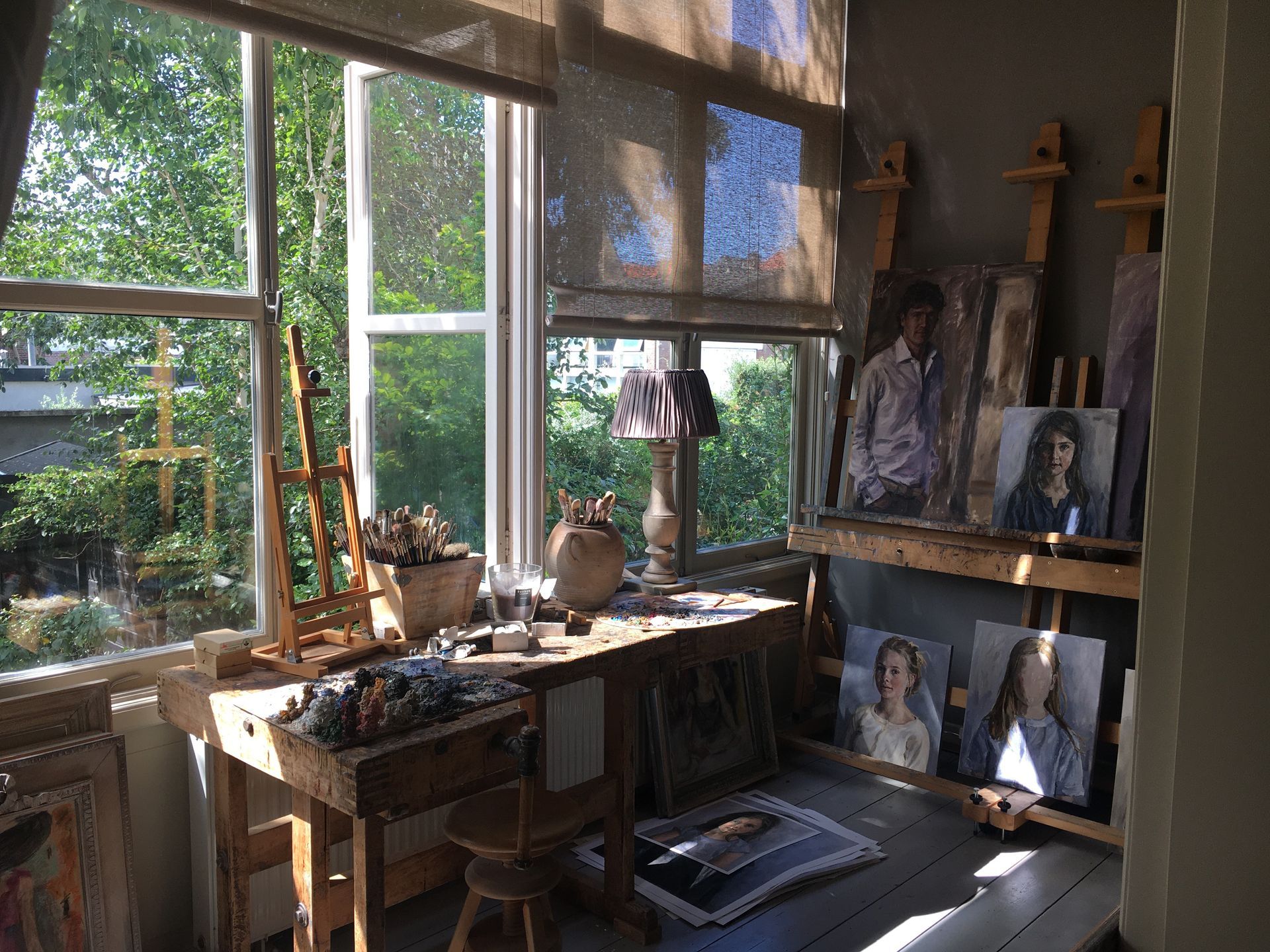 Een kunstenaarsatelier met tentoongestelde schilderijen en een groot raam. atelier rianne smit.